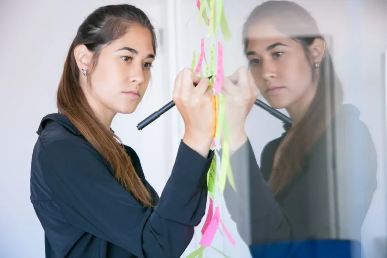 beautiful-young-latin-businesswoman-writing-sticker-with-marker-concentrated-professional-female-manager-sharing-idea-project-making-note_74855-6747